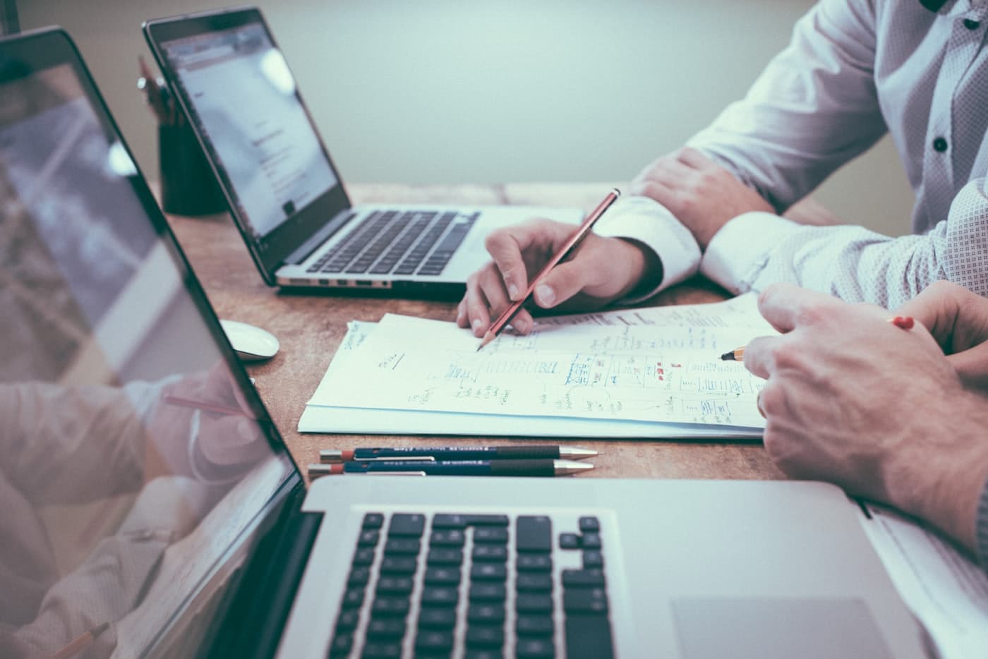 Two HR professionals reviewing printed policy documents and notes together at a desk